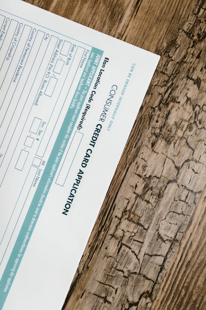 A credit card application form placed on a wooden surface, shot from above.